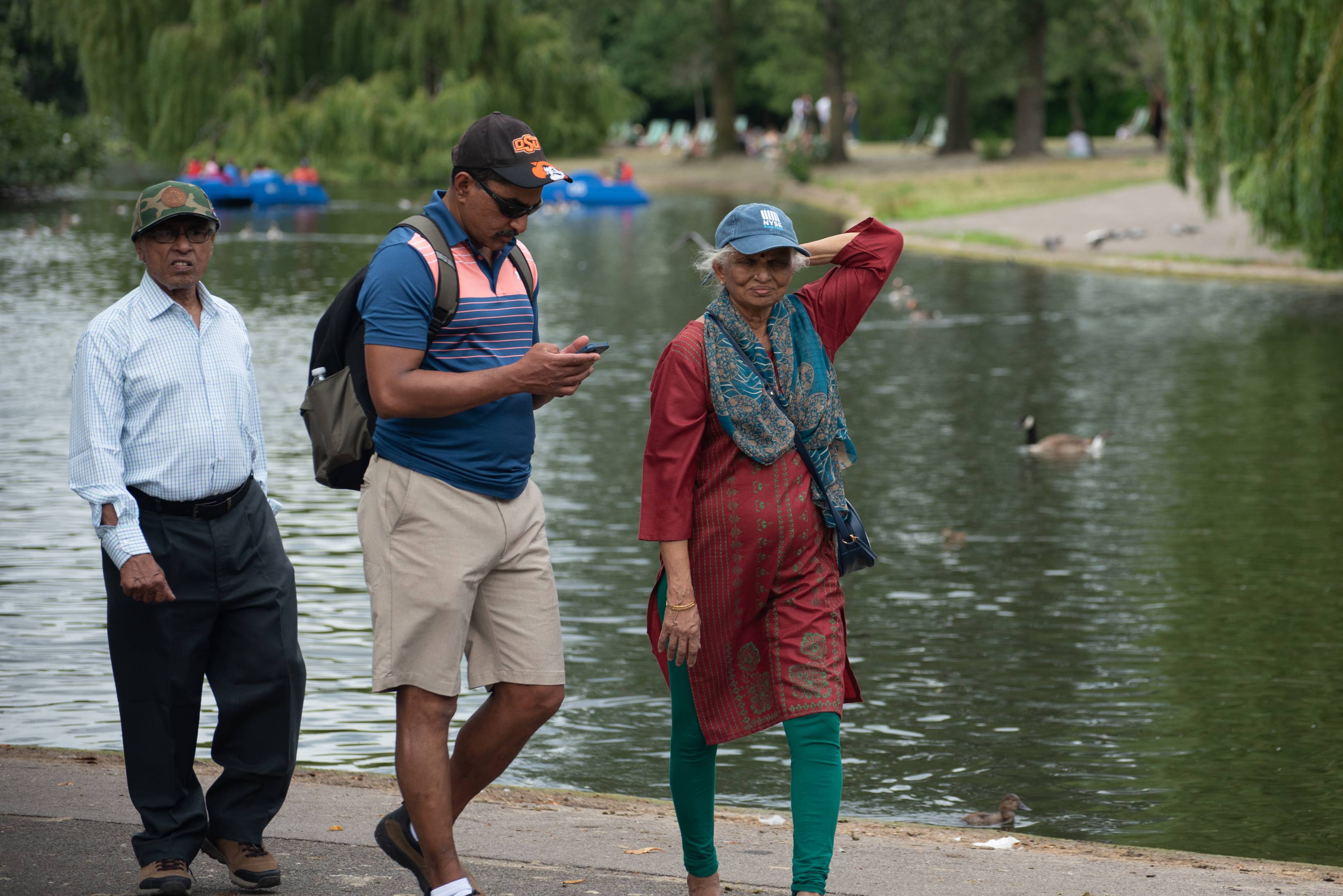 Three friends walking by a lake in a park