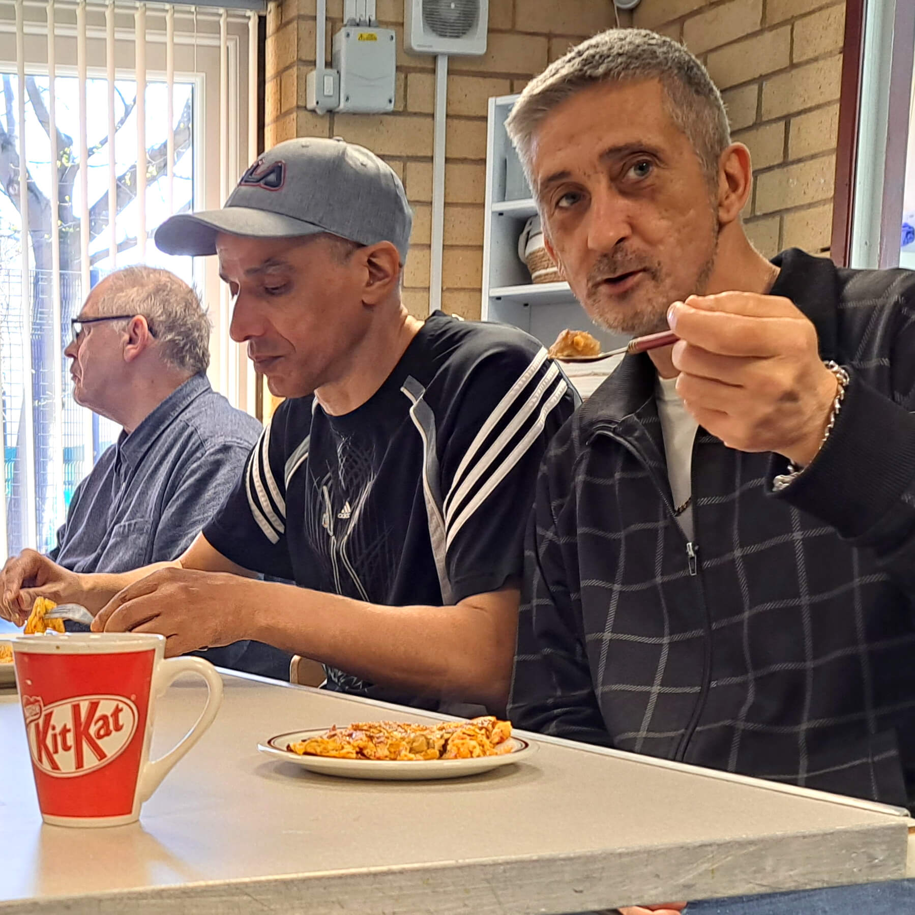 Three men at a table eating.
