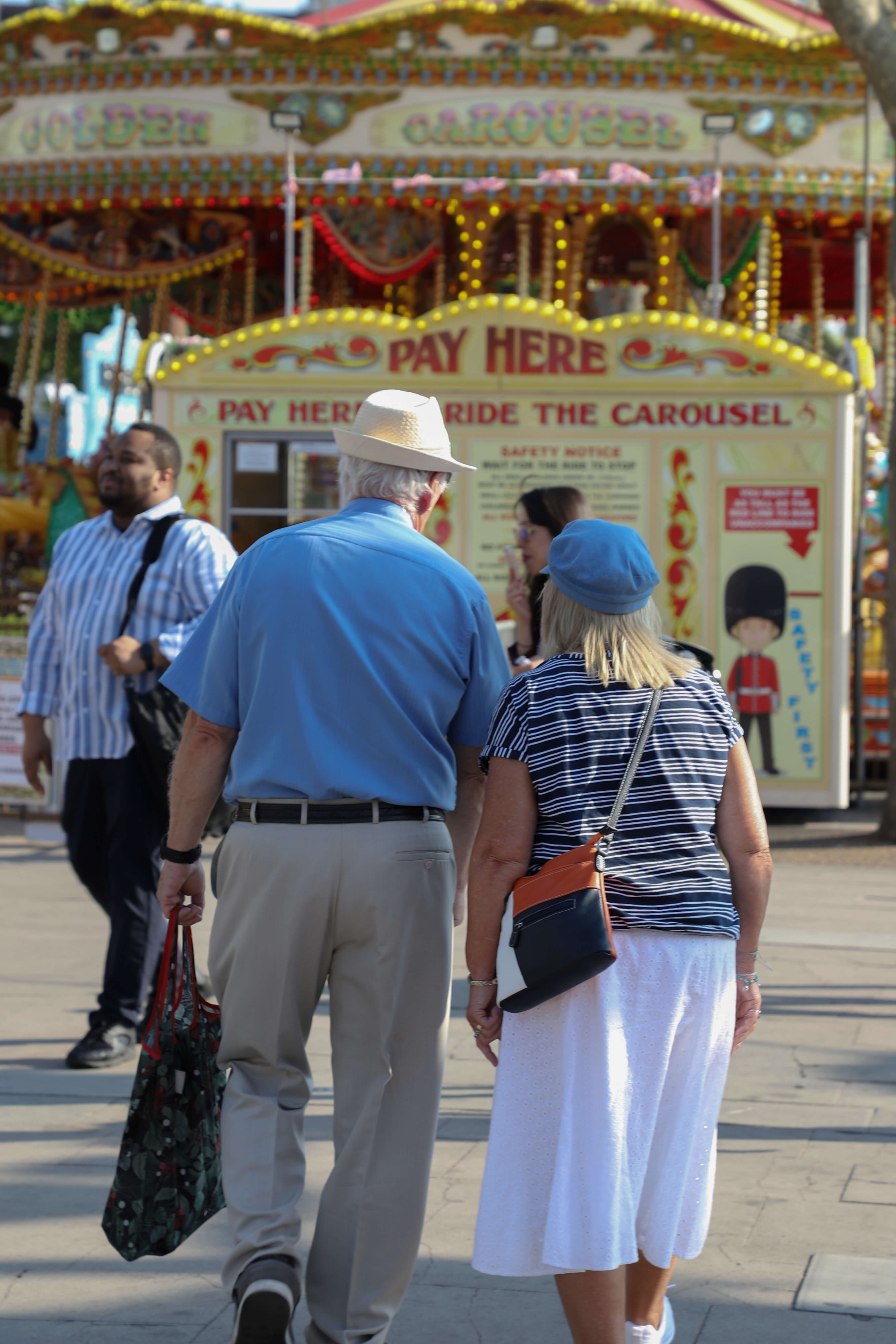 An older couple holding hands in a theme park.
