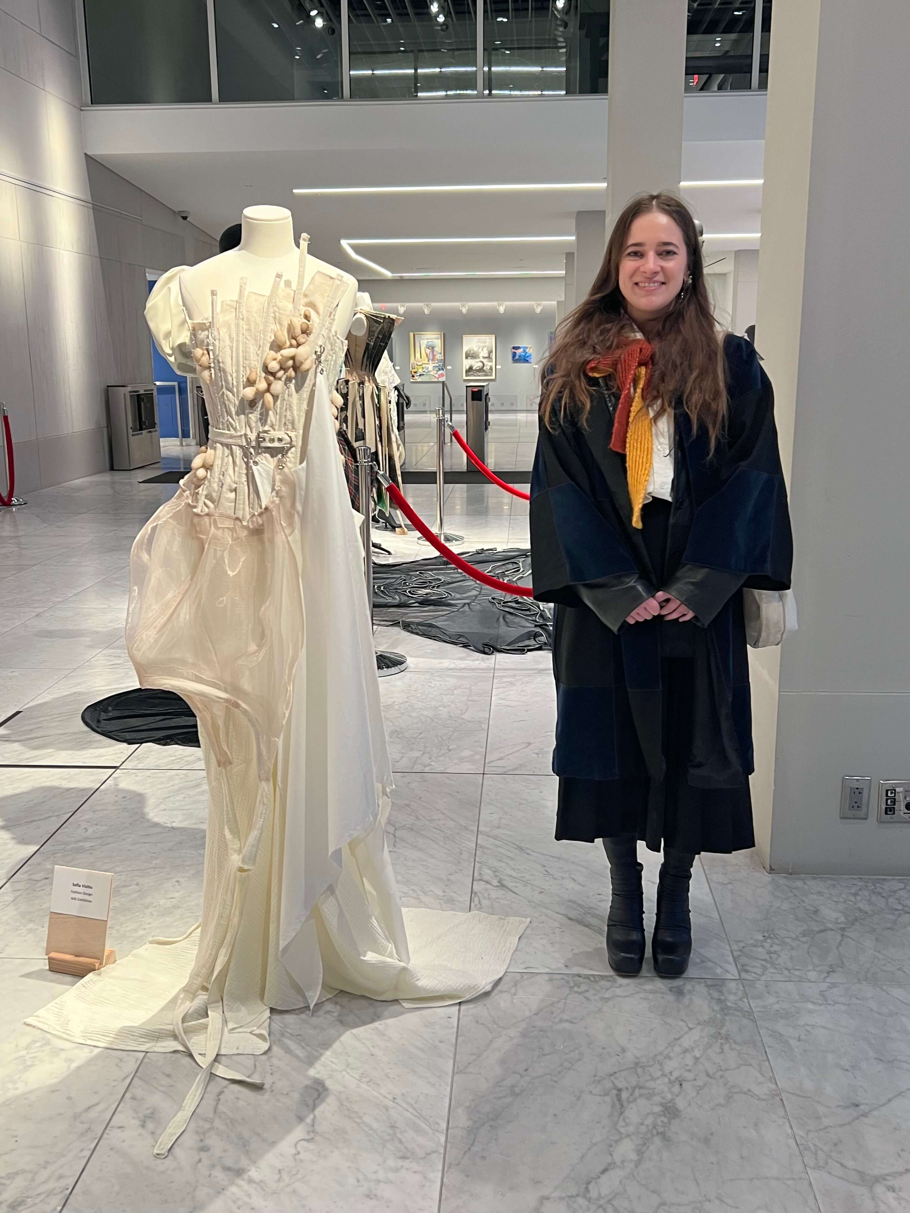 Sophia standing next to one of her fashion creations