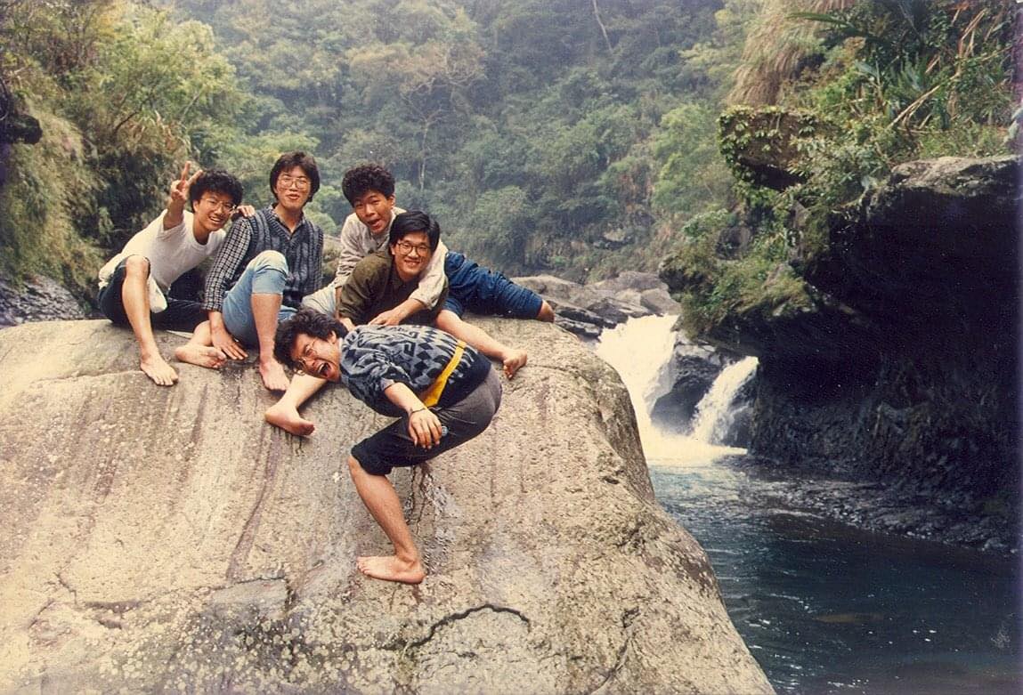 Kris when in his 20s on a rock by a river with his friends