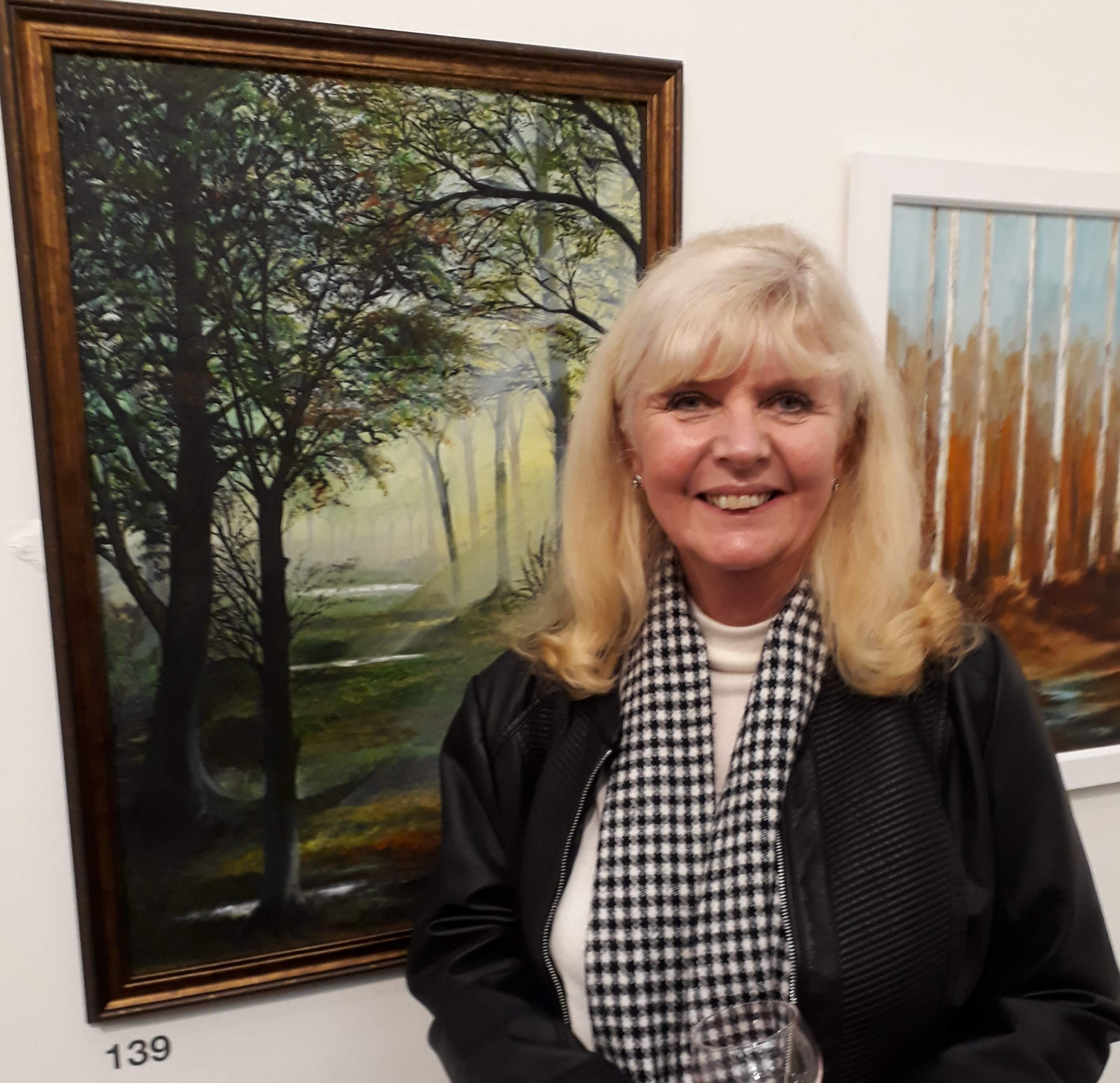 Carol in front of her forest painting chosen for the exhibtion.