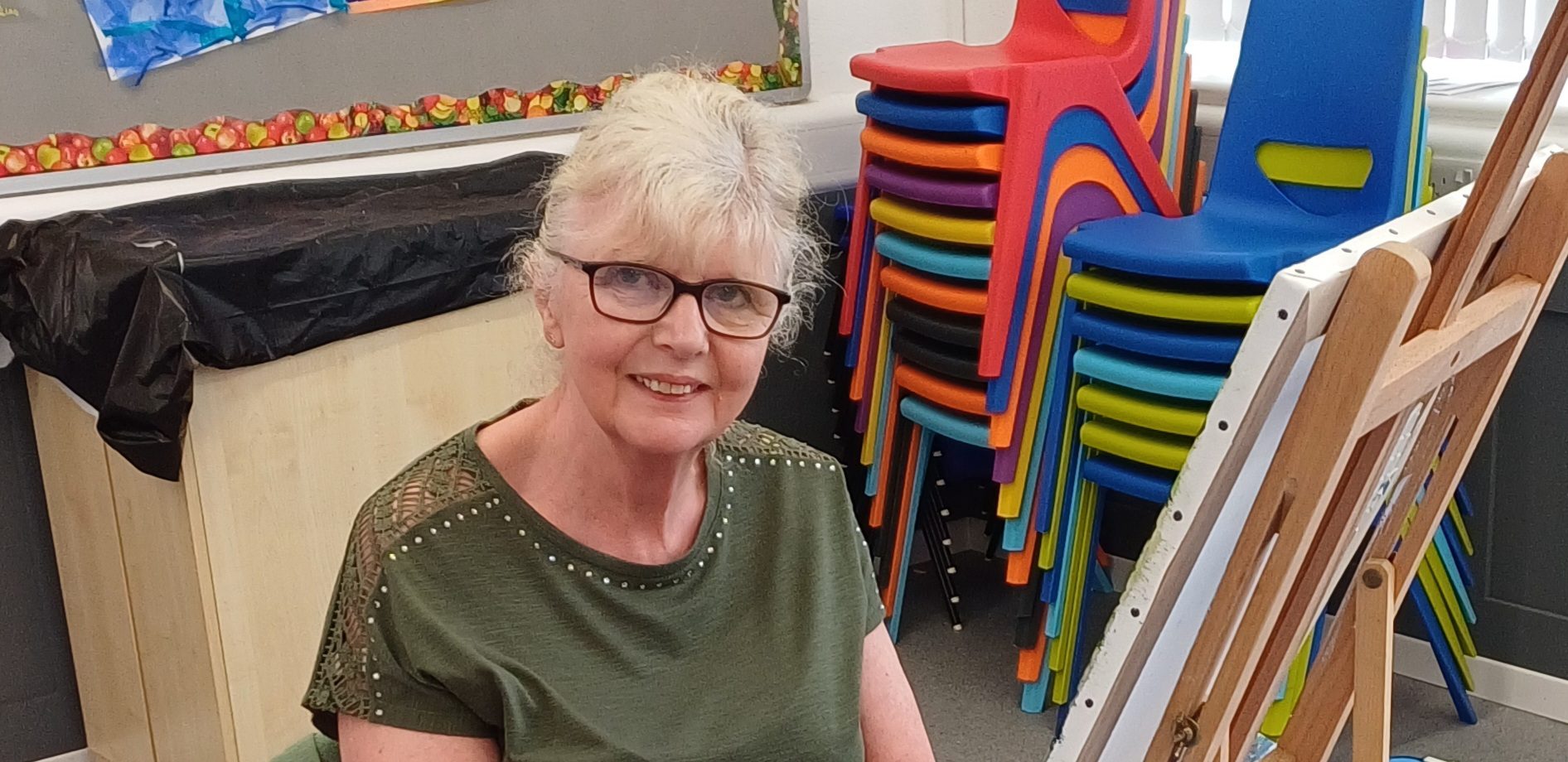 Carol painting at her easel at one of her arts classes