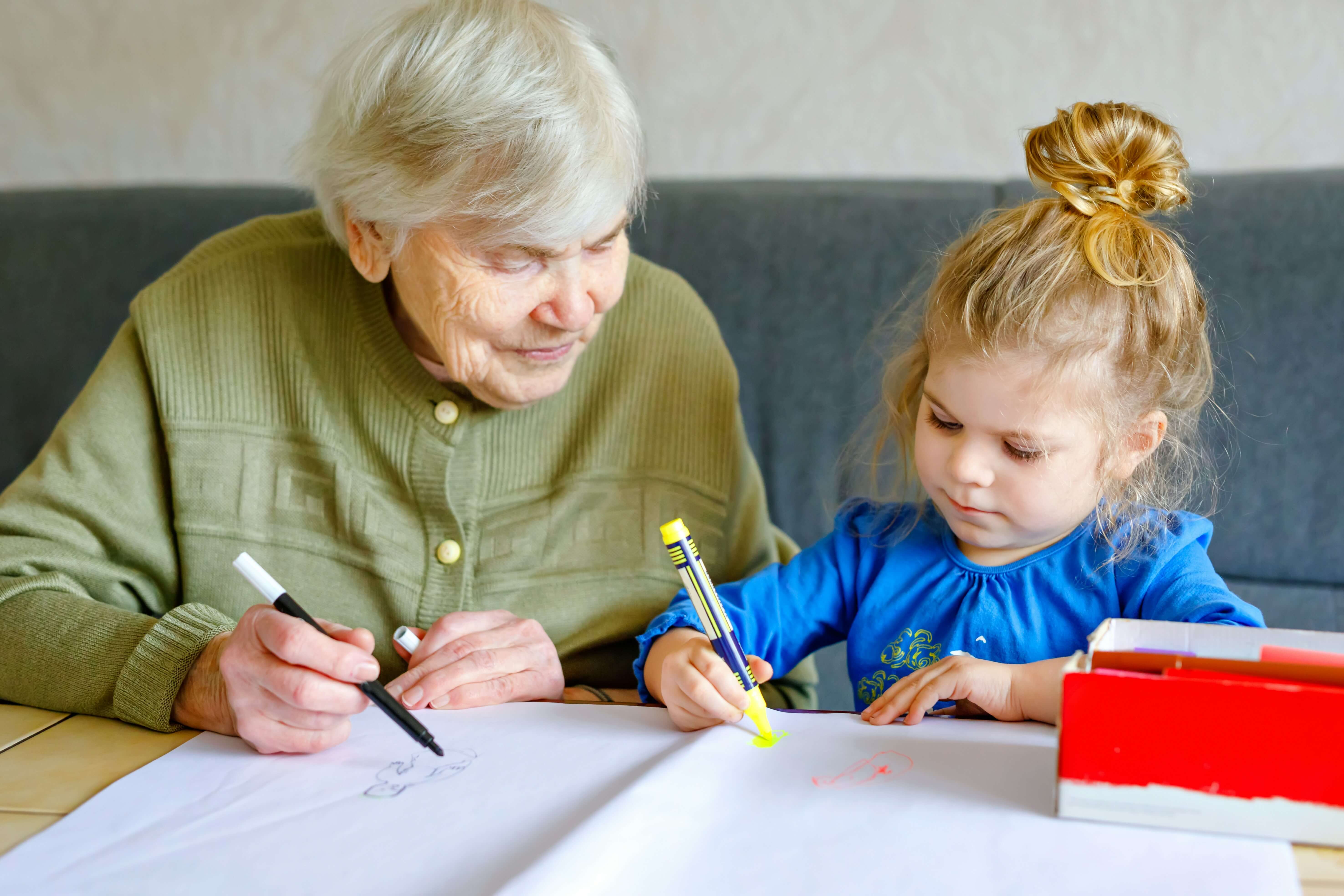 Older woman and young girl with pens and paper