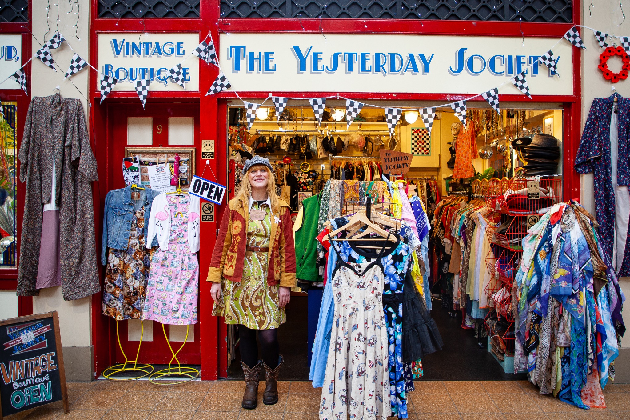 Woman market trader selling second hand vintage clothes looking at the camera