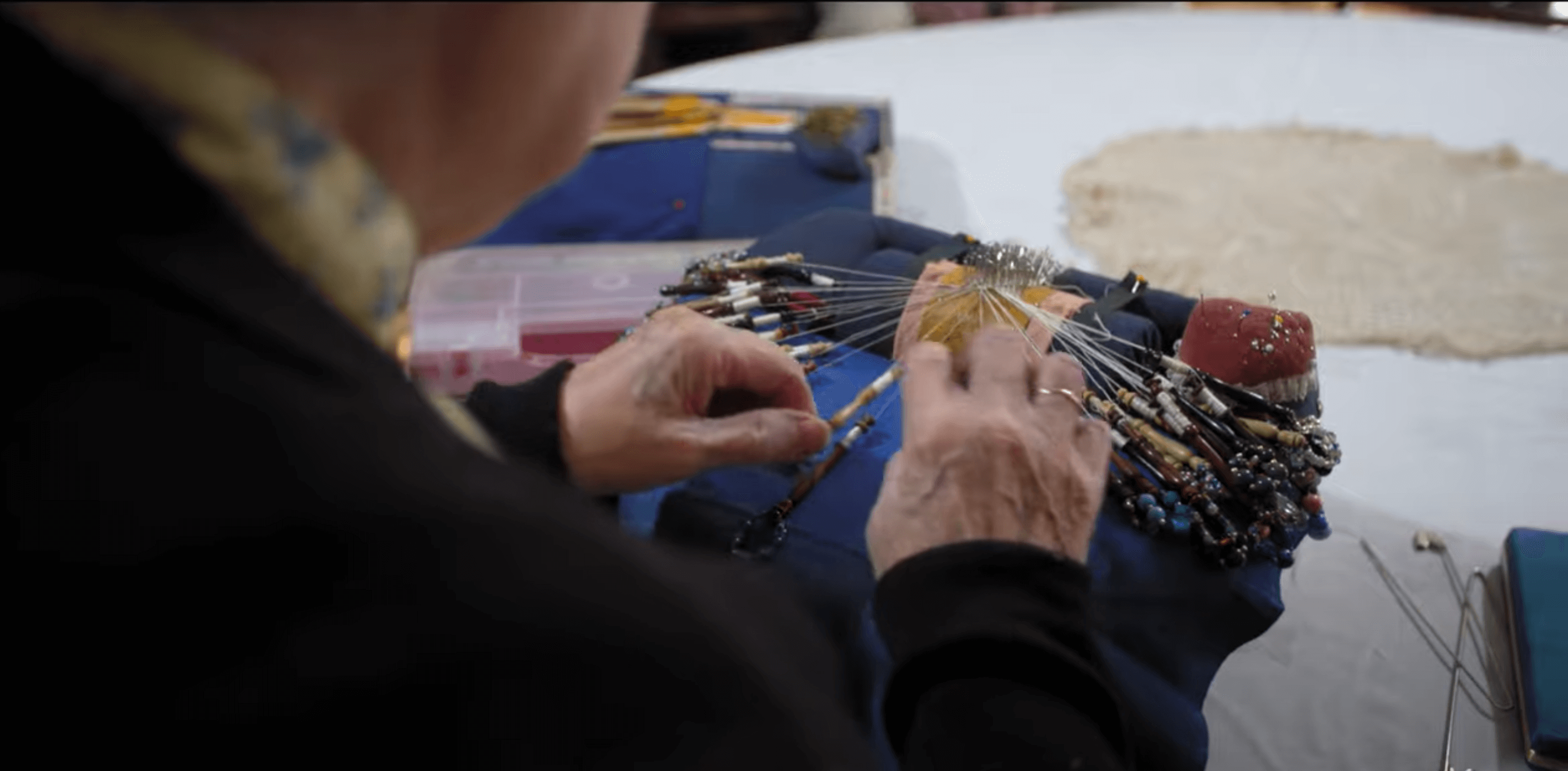 Norma making lace using her lace cushion.