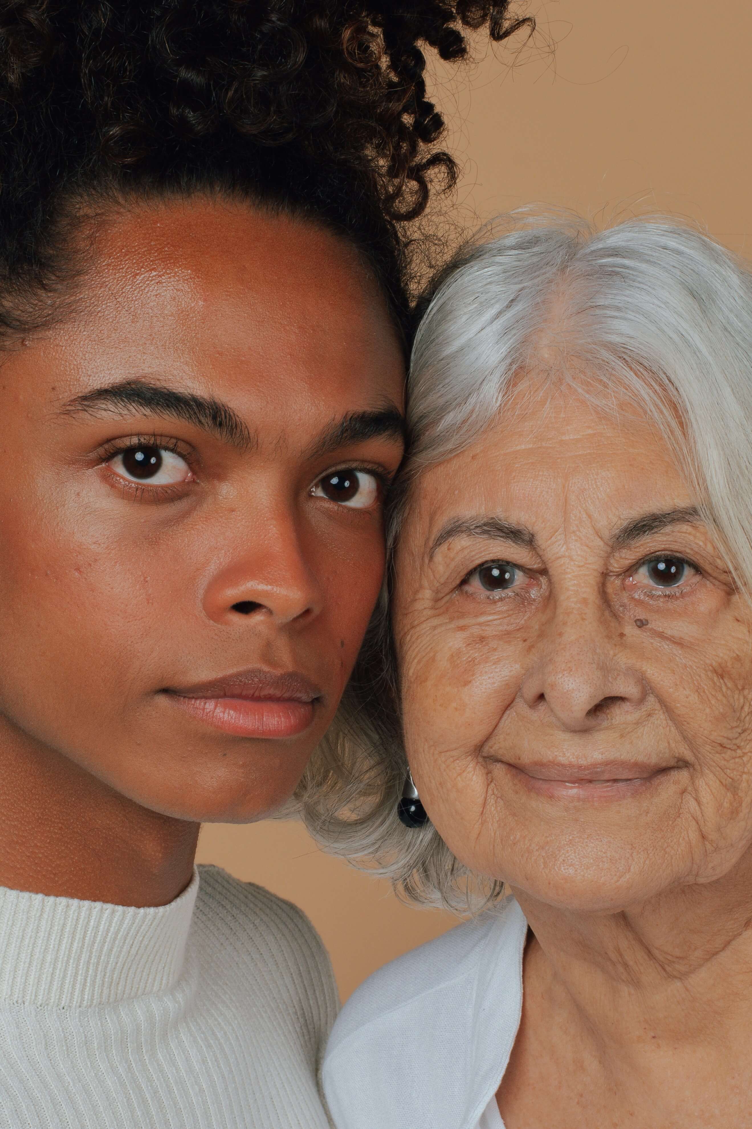 Older other and younger woman side by side. POrtrait shot. Young skin and older skin with wrinkles an dboth looking gorgeous