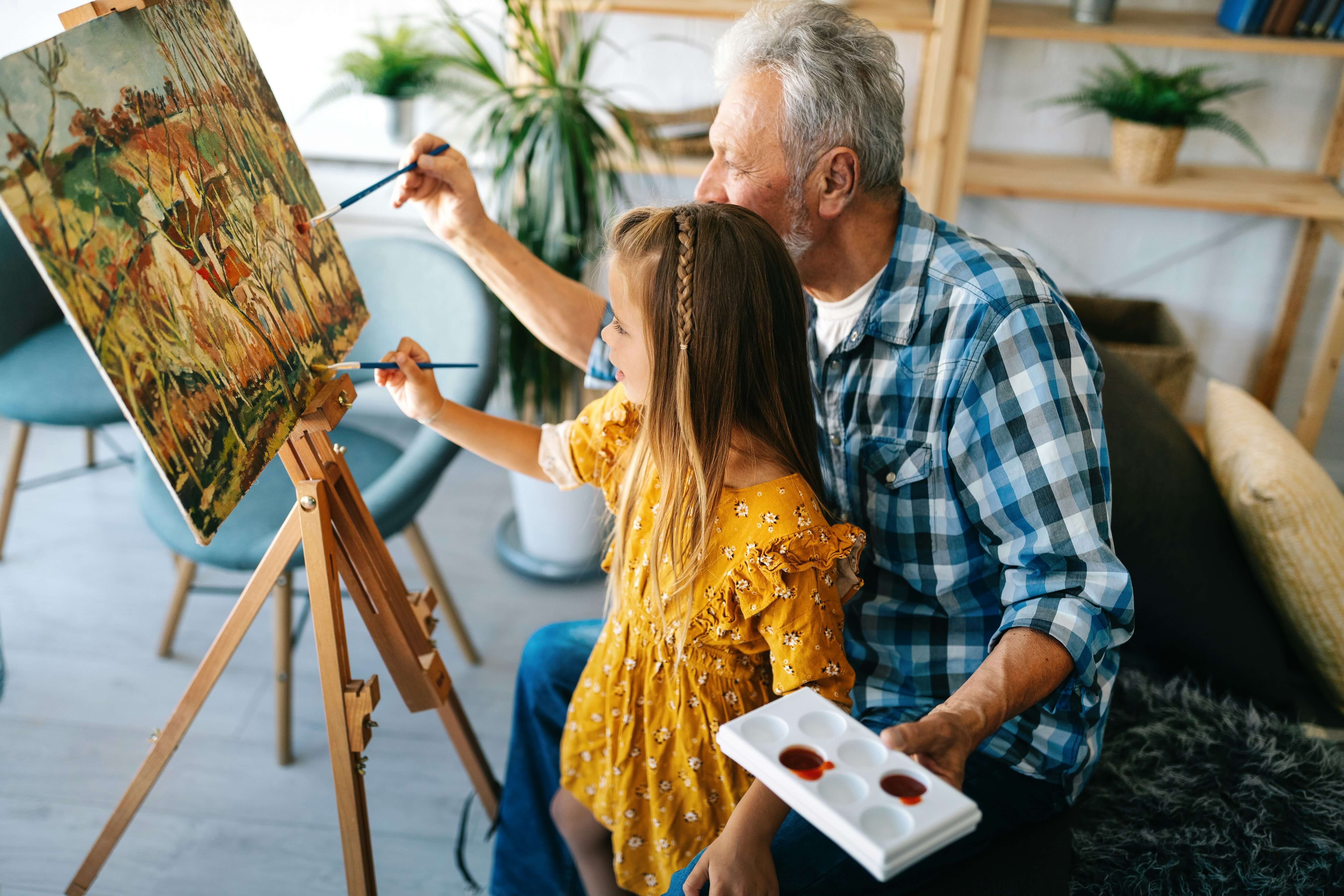 Granddaughter and grandfather painting together