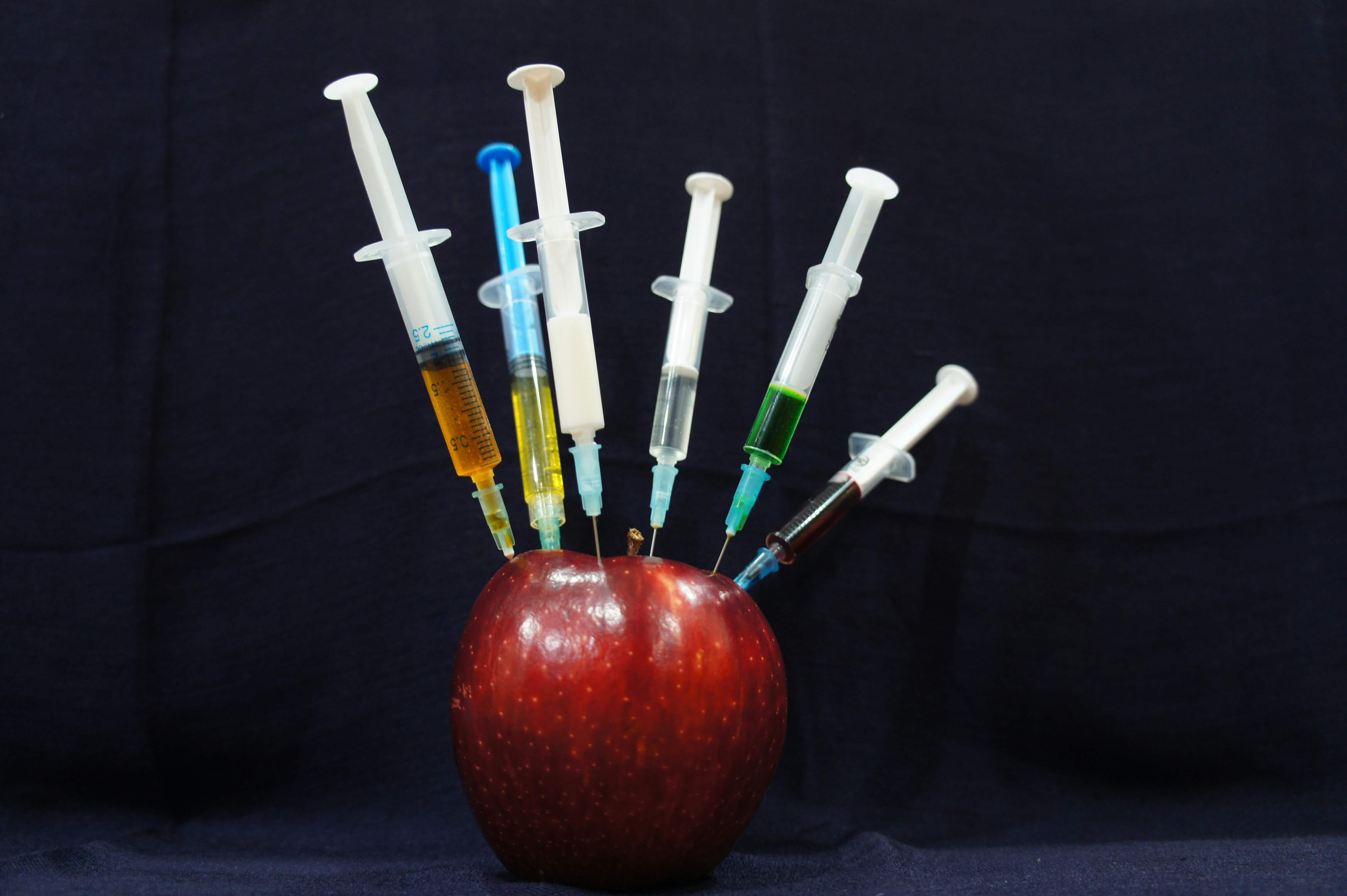 An apple pierced by lots of syringes