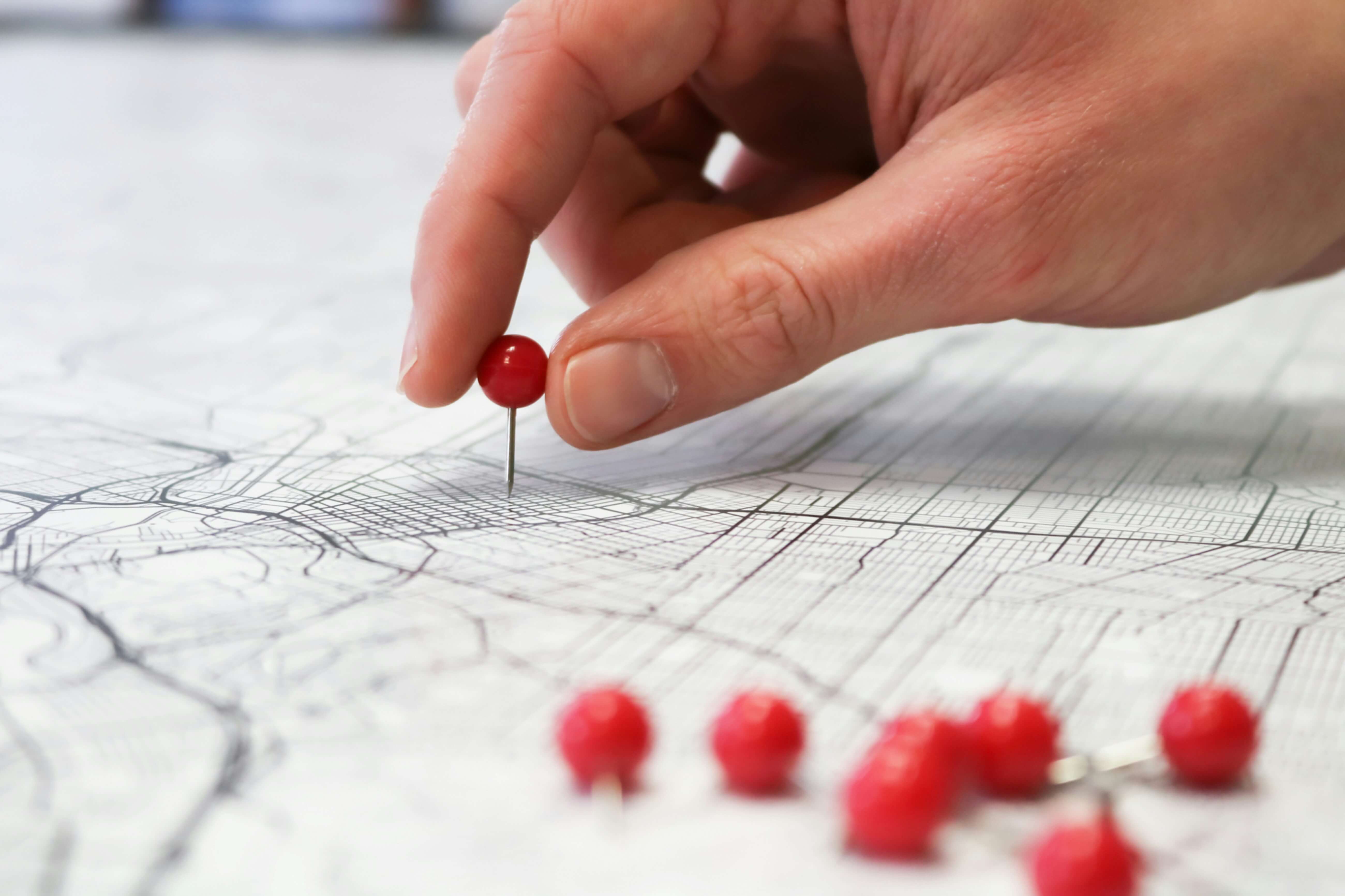 A hand putting pins into a map