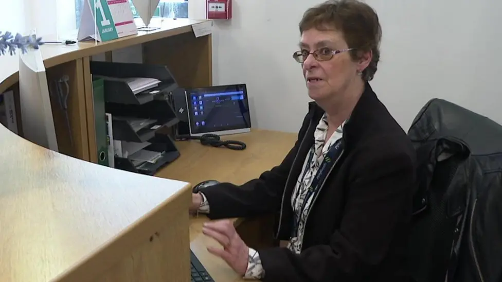 Linda Booth sitting at her desk