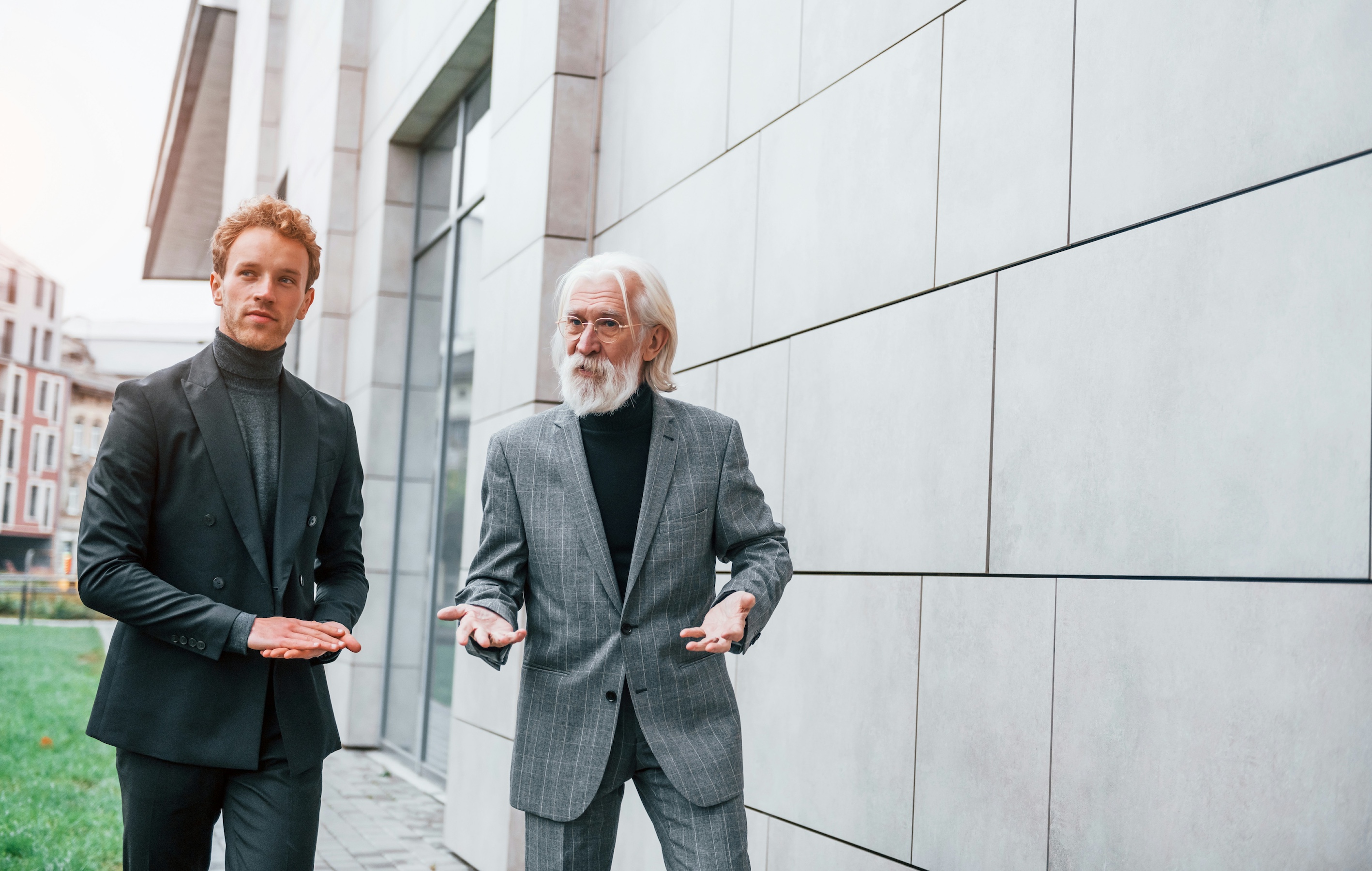 Older man and younger man in work clothes walking and talking
