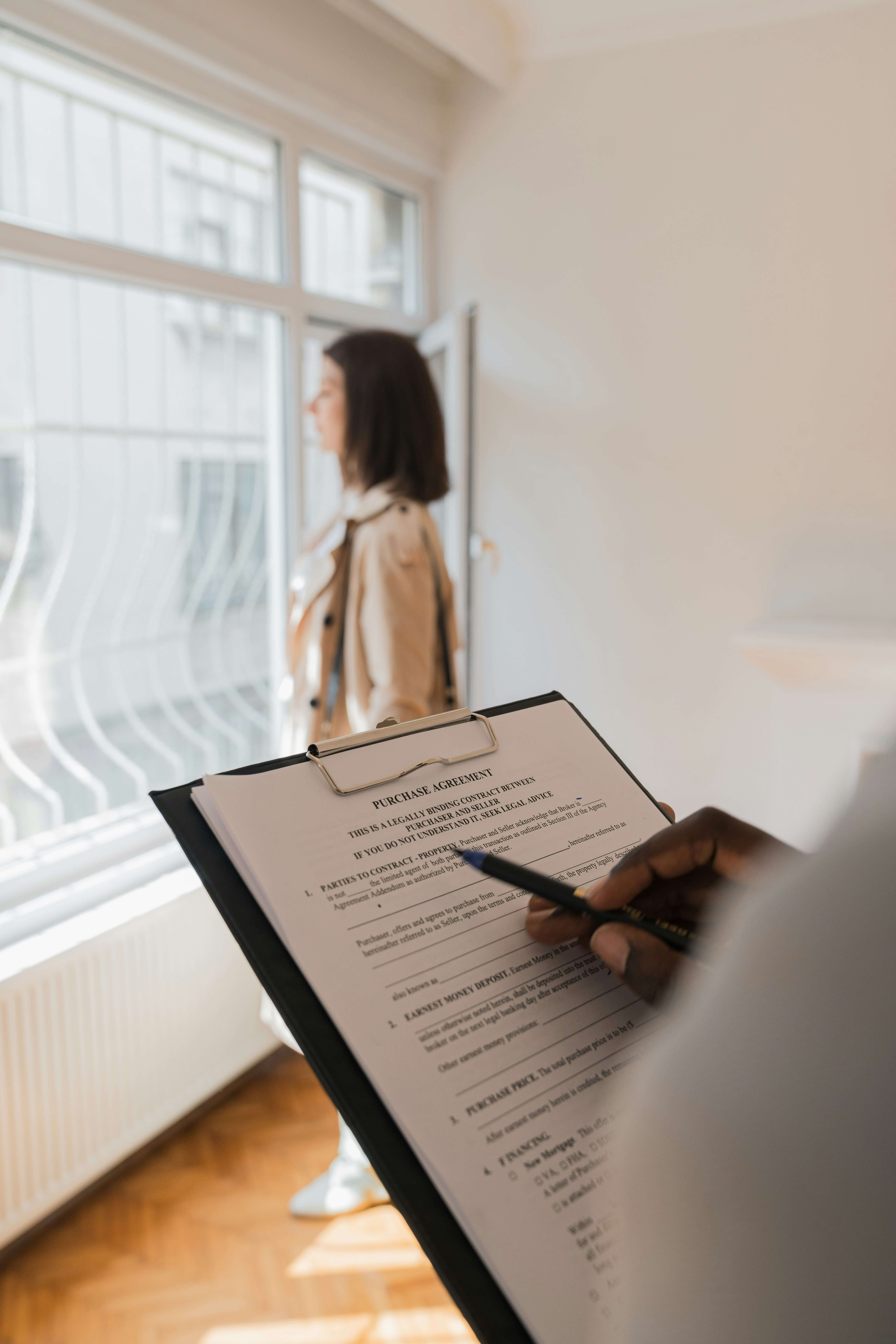 A person with a clipboard and questionanire with a person looking out the window
