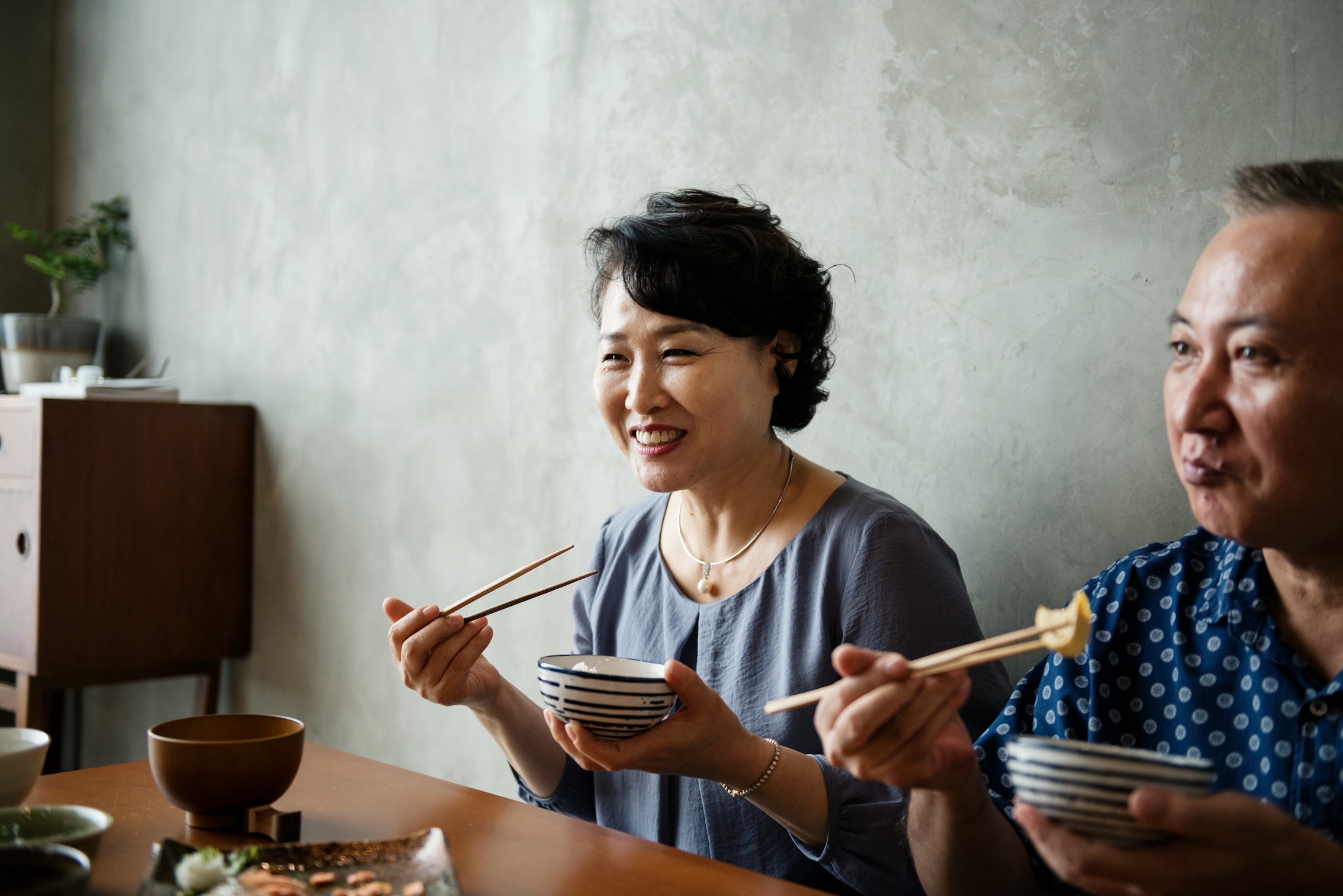 Two women smiling, eating rice with chopsticks