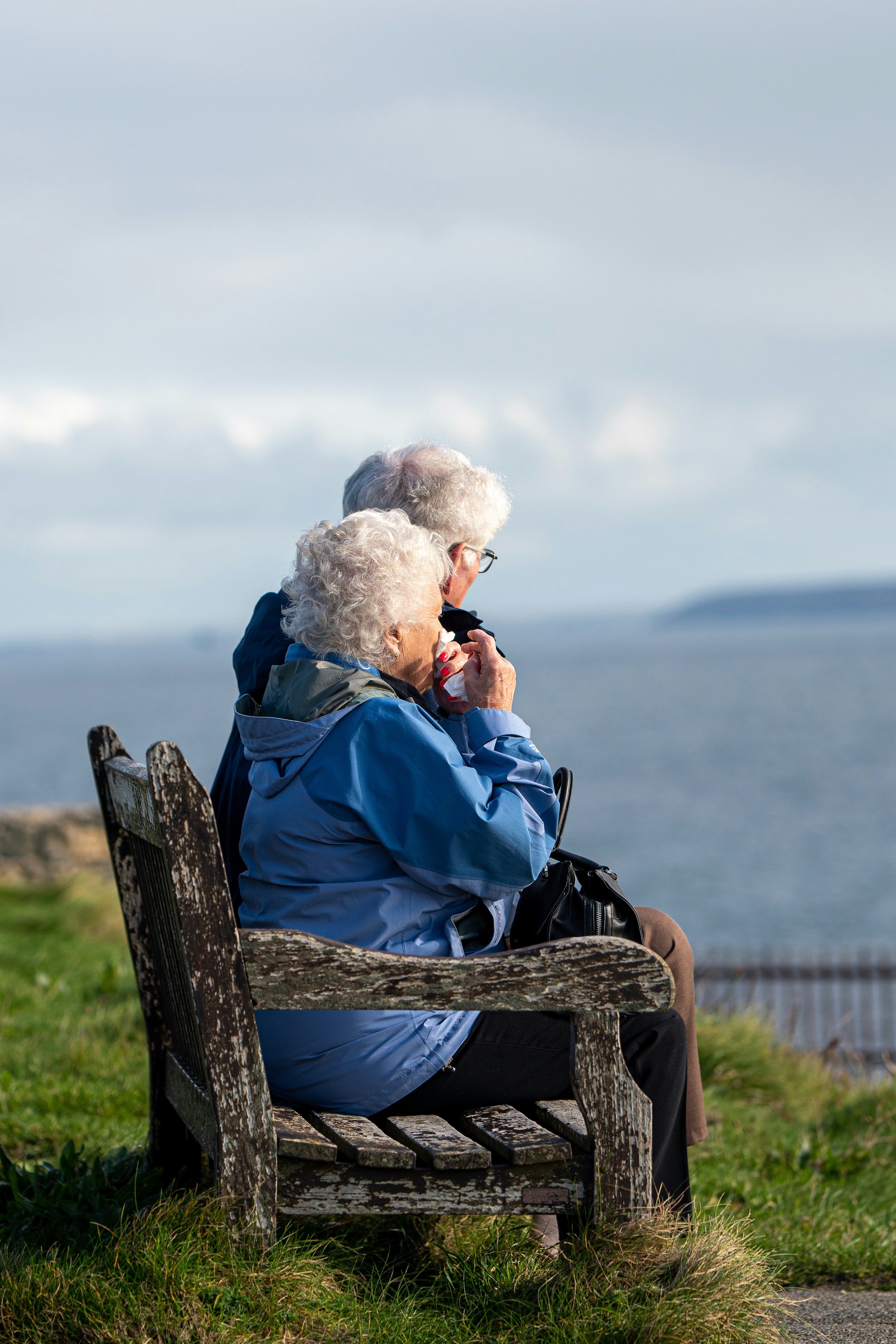 Two women sitting on a bench looking at the view